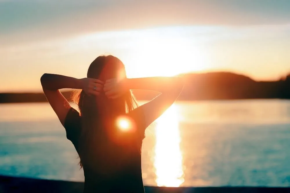 mental-health-support-colorado - Mindful Springs Woman standing on the shore looking at a sunrise