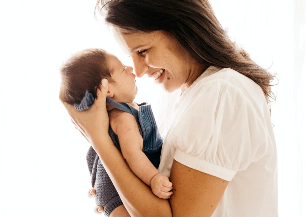 mother looking lovingly at infant and smiling