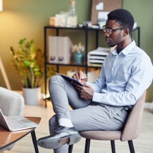 therapist taking notes on video call on laptop