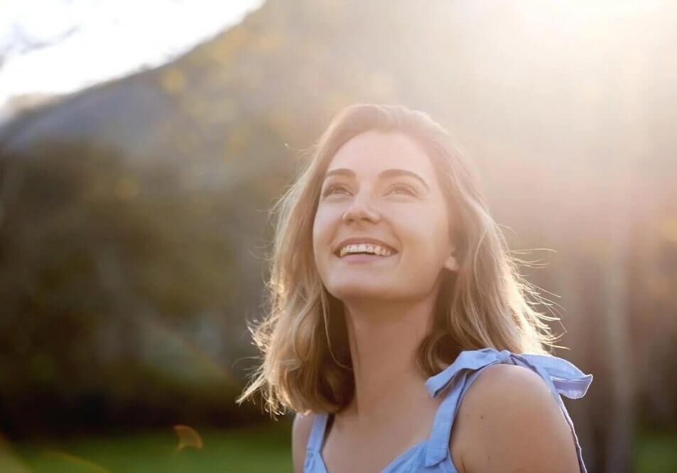 woman outdoors looking up at sky and smiling