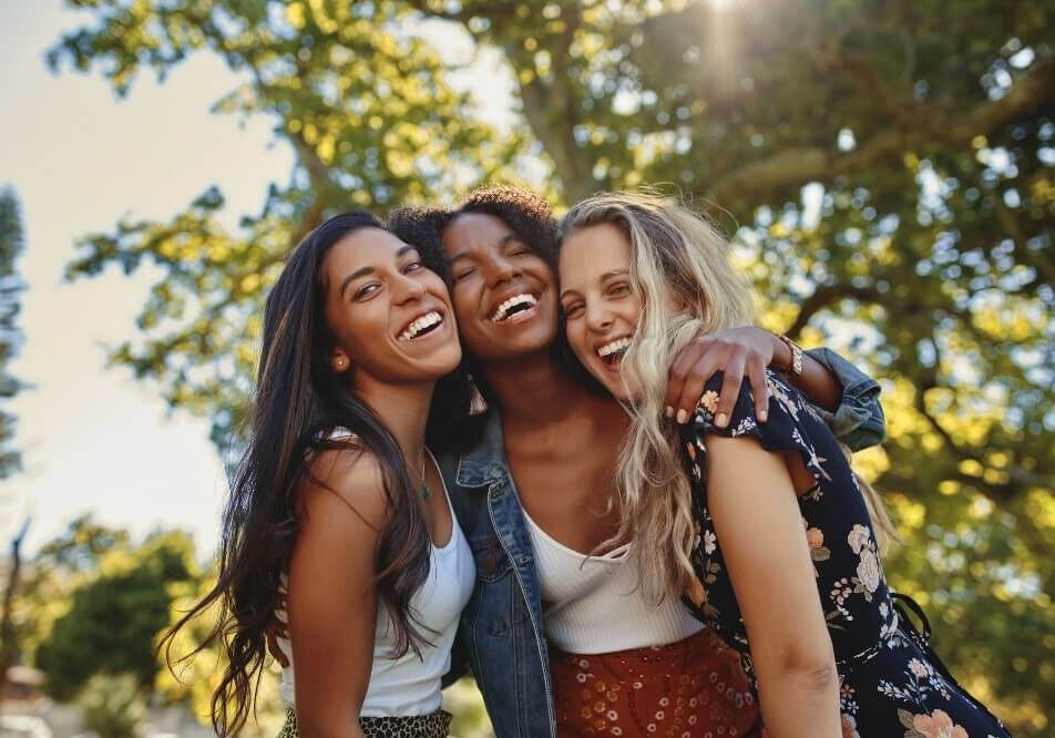 group of women with arms around each others shoulders smiling