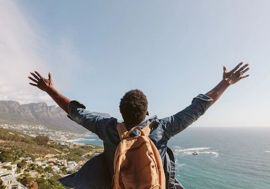 man outdoors with arms stretched up to the sky