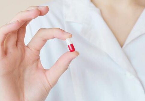 woman holding up red and white pill