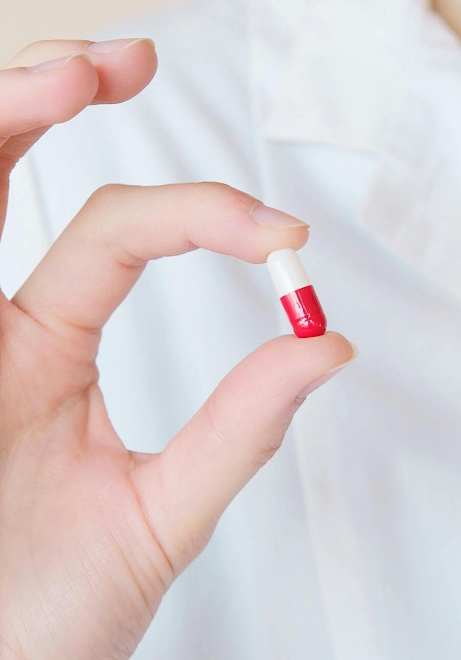 nurse holding up red and white pill